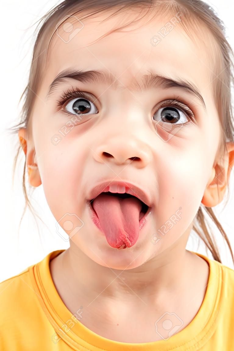 A little girl grimaces with her tongue hanging out on a white background.