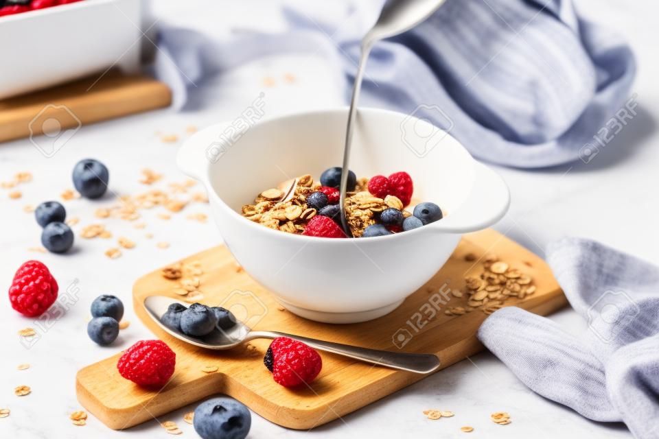 Hintergrund des Frühstücksessens. Müsli mit Milch und Beeren auf einem weißen Tisch.