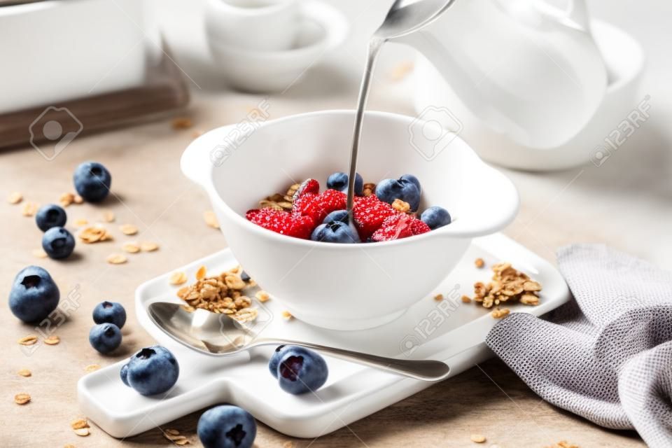Hintergrund des Frühstücksessens. Müsli mit Milch und Beeren auf einem weißen Tisch.