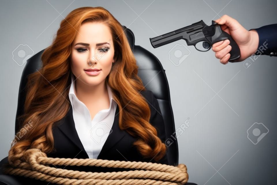 Mulher de negócios ligada a uma cadeira com corda e apontar para a cabeça com uma arma isolada em um fundo branco