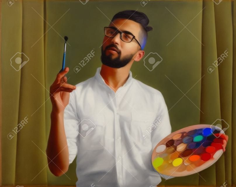 Портрет молодого мужчины художника держит кисть и смешивать цвета маслом на палитре.
