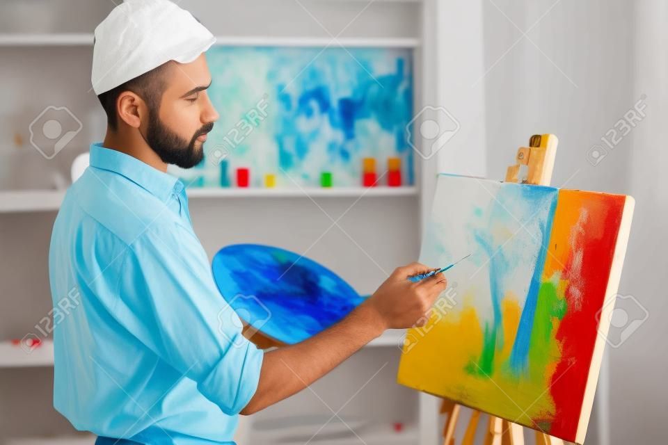 Vista laterale del pittore di grande talento mentre sta dipingendo la sua foto.