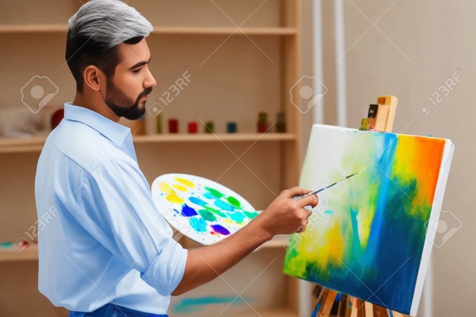 Vista laterale del pittore di grande talento mentre sta dipingendo la sua foto.