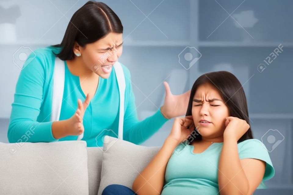 Проблемы в отношениях между поколениями концепции. Подросток закрыл уши руками, а ее мама кричит на нее.