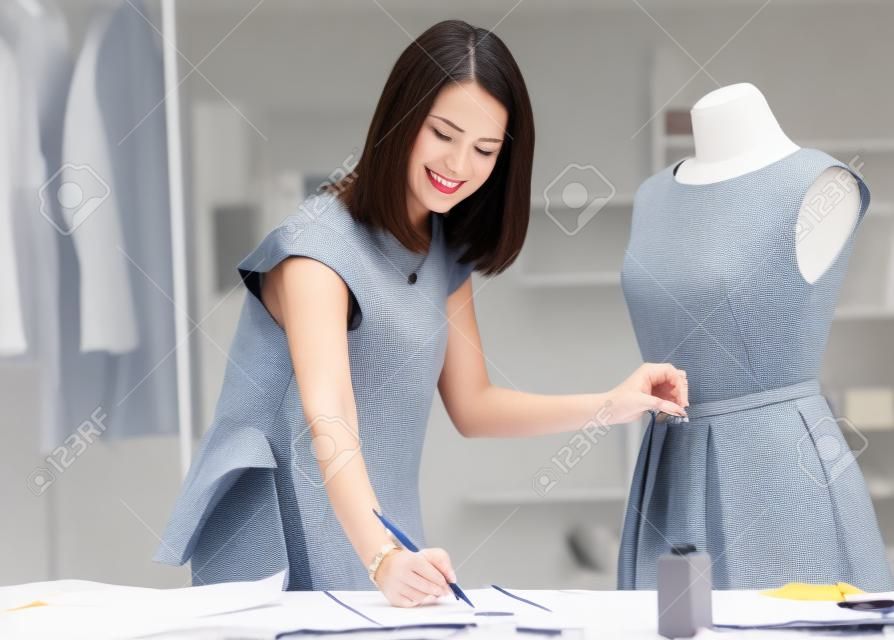 Female fashion designer taking measurement and writing it down.