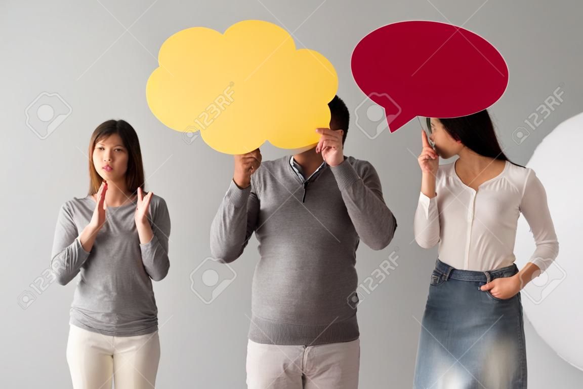 Beautiful young people are holding speech bubbles, on gray background