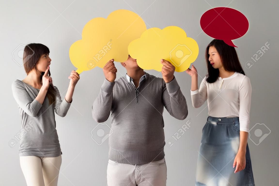 Beautiful young people are holding speech bubbles, on gray background