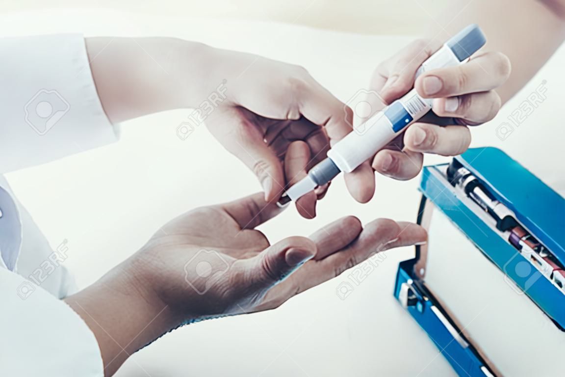 Doctor Taking Blood Sample from Boy's Finger. Diabetes Concept. Sugar in Blood. Healthcare Concept. Young Man in Uniform. White Coat. Medical Equipment. Boy in Clinic. Glucometer in Hand.