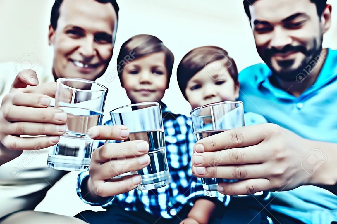 Smiling Family Drinking Water in Glasses at Home. Father and Son. Smiling People. Parenthood Concept. Family at Home. Happy Family. Glass of Water. Young Woman. Family in Dining Room.