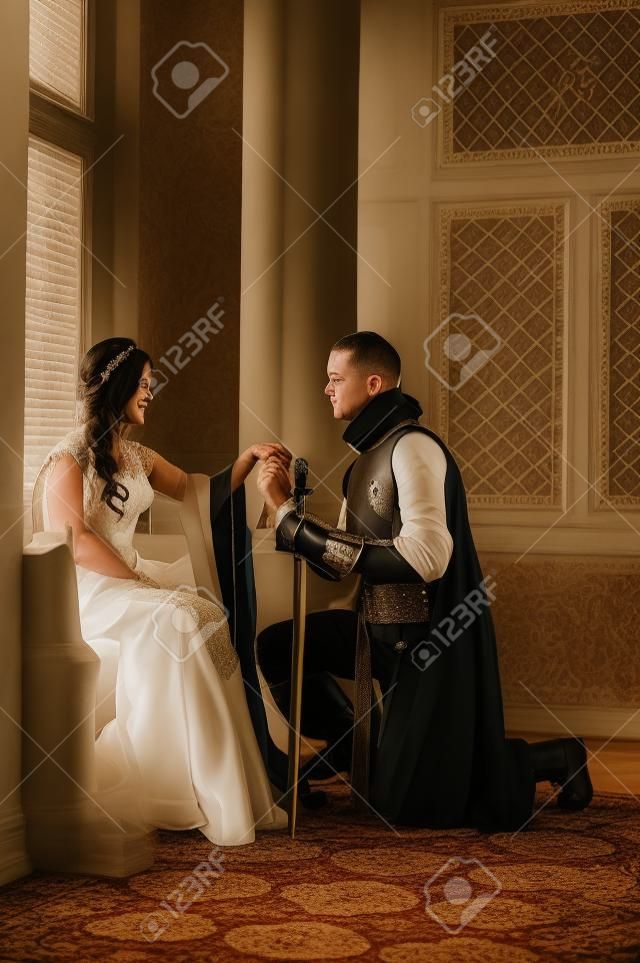 Un jeune chevalier se met à genoux devant sa dame son v?u d'engagement prononcer.