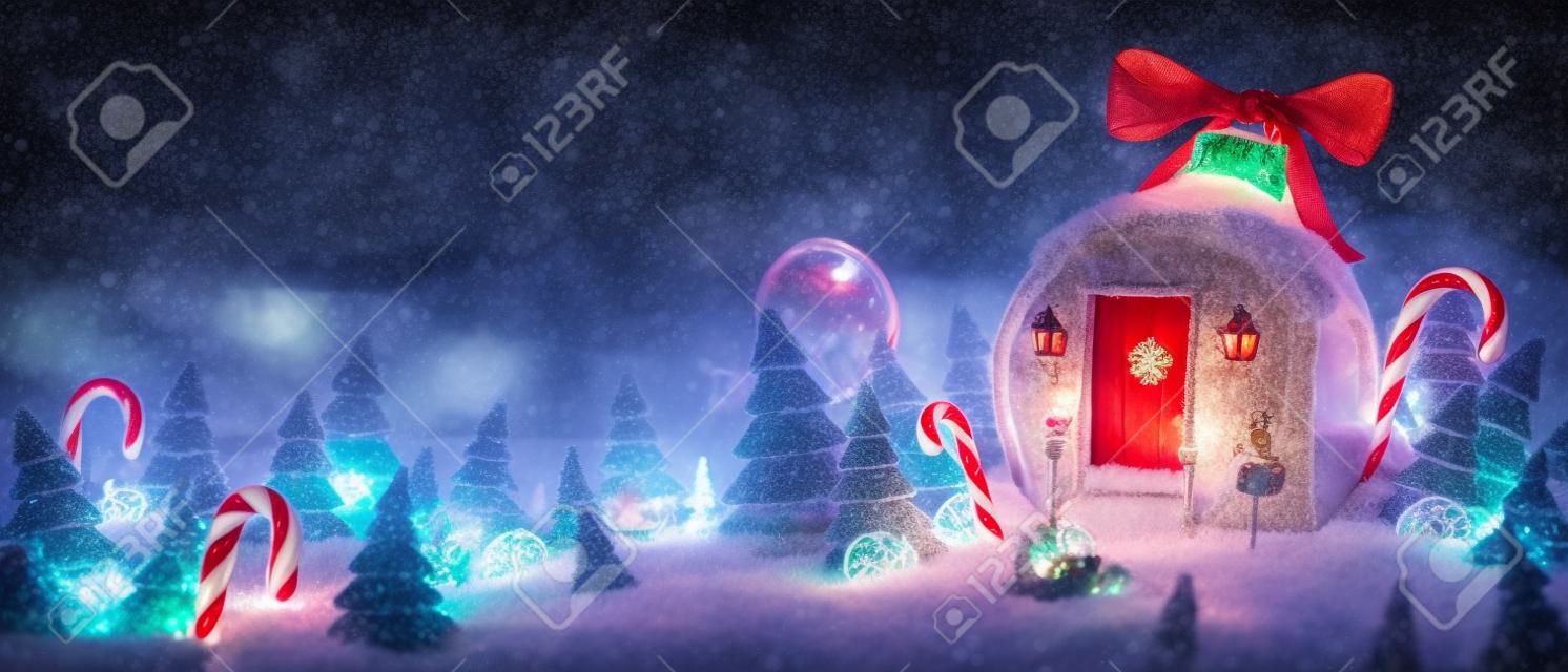 Verbazingwekkend sprookjeshuis ingericht bij Kerstmis in de vorm van kerstbal met rood lint en kerstverlichting in magisch bos met snoepstokken. Ongebruikelijke kerst 3d illustratie ansichtkaart.