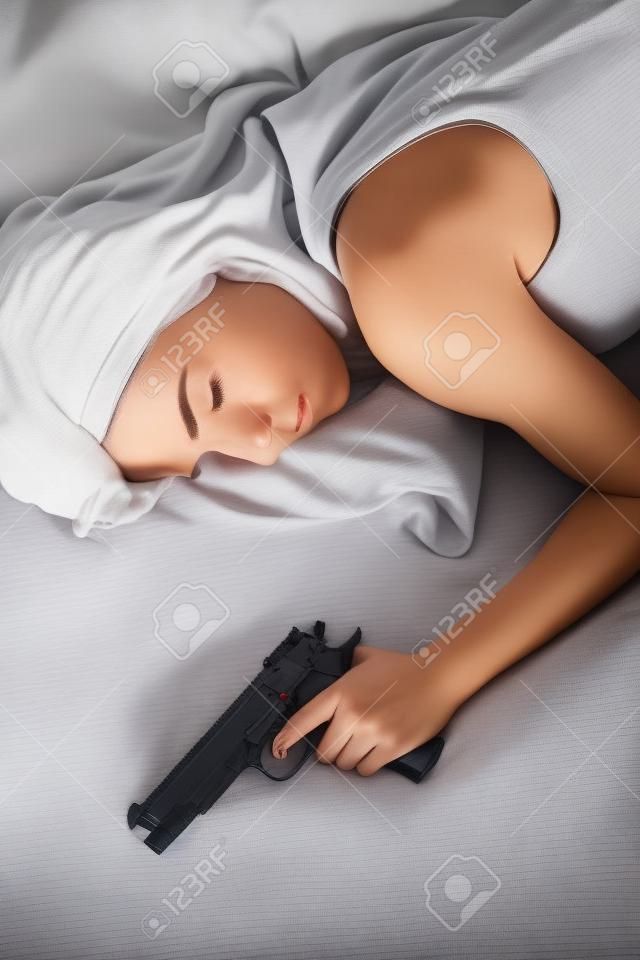 銃武器ホーム セキュリティに手と寝るベッドで女性