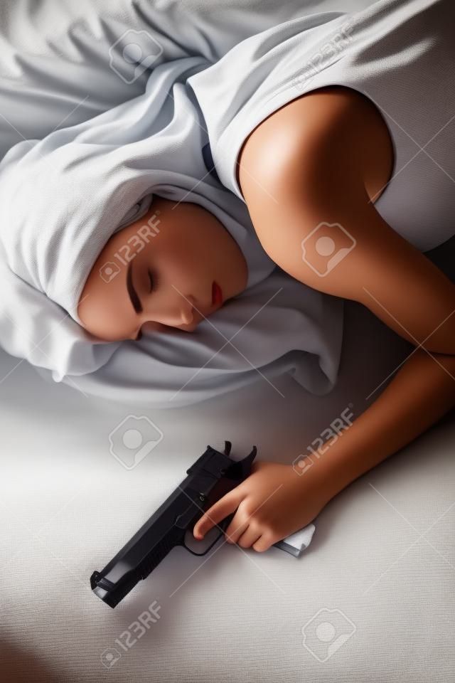 Kobieta w łóżku śpi z ręką na pistolet bezpieczeństwa w domu broń
