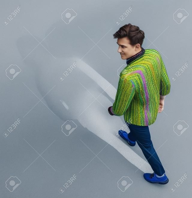 Vista superior retrato de un hombre joven en ropa colorida caminar sobre backgorund gris