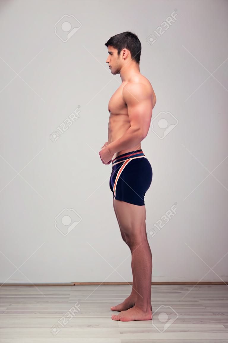 Side view portrait of a young muscular man standing in studio