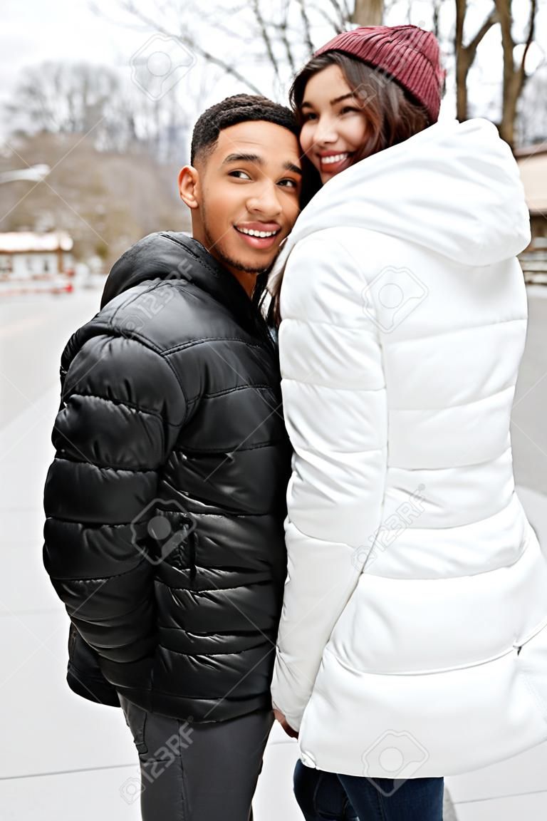 Cheerful young couple holding hands and looking back outdoors in winter