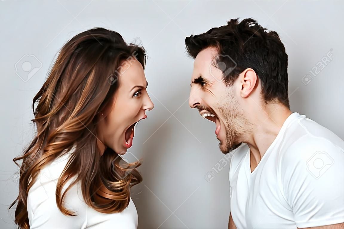 Couple qui crie en regardant les uns les autres. Fond gris isolé