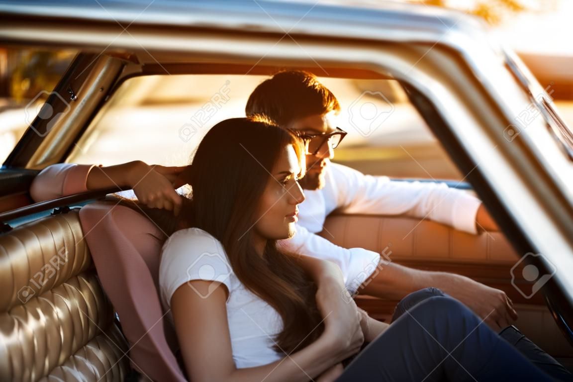 Retro bir arabanın içinde otururken birlikte rahatlatıcı genç güzel çift