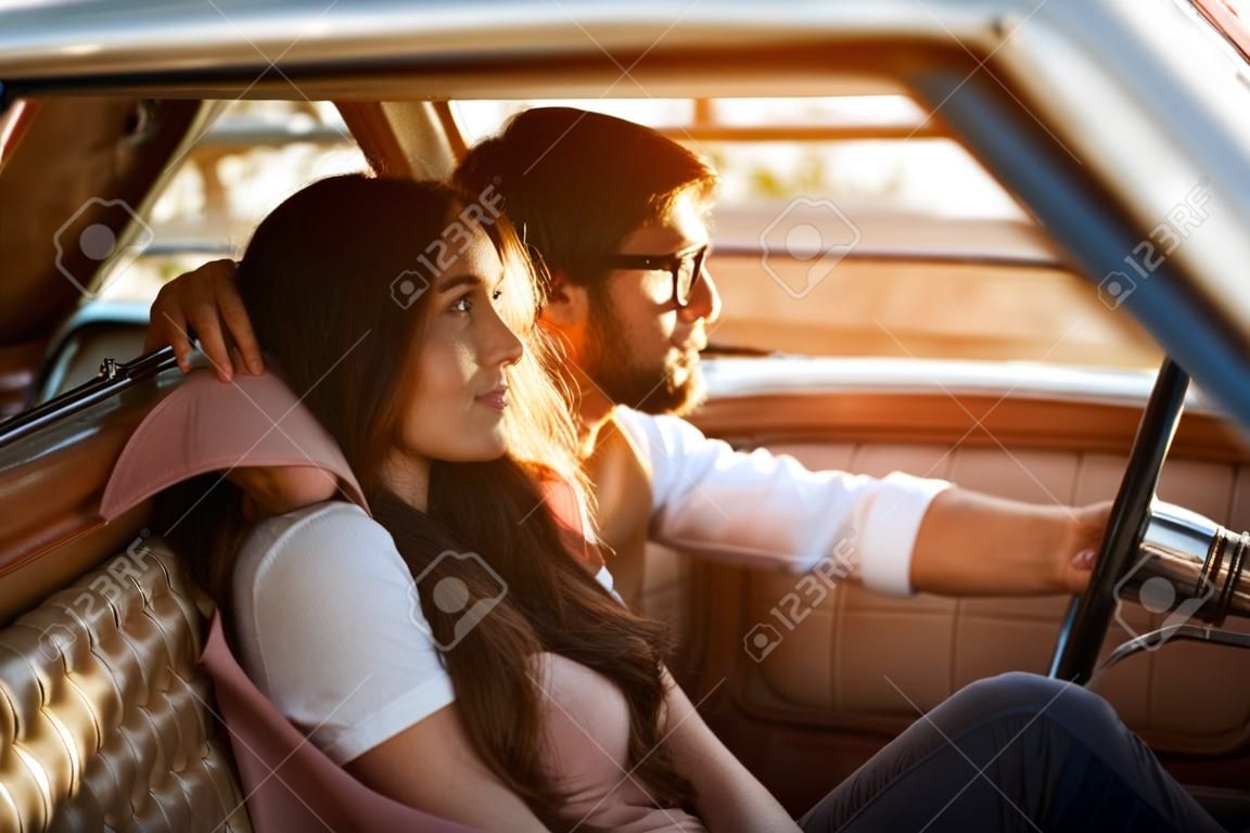 Jeune beau couple se détendre ensemble assis dans une voiture rétro