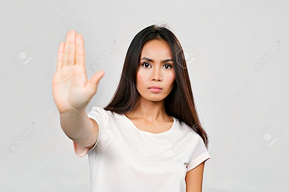 站立与被伸出的手陈列中止姿态的一名严肃的年轻亚裔妇女的画象被隔绝在白色背景
