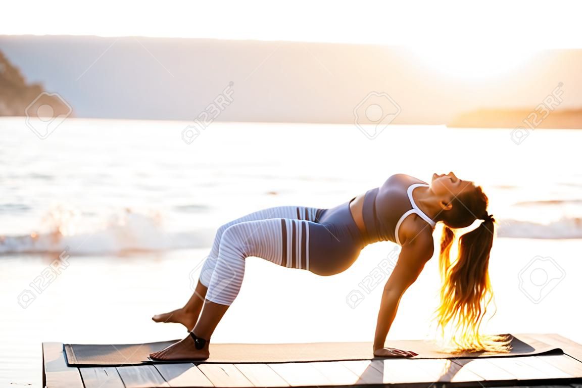 Das Bild einer erstaunlich starken jungen Fitnessfrau im Freien am Strand macht Yoga-Dehnübungen.