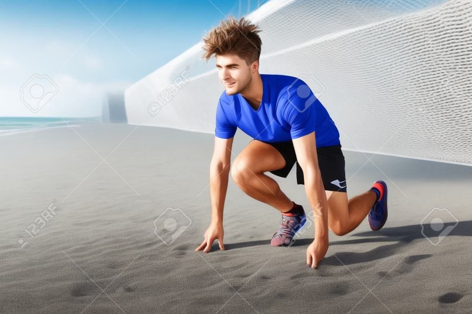 Image of handsome young guy sportsman runner standing ready to start outdoors on the beach.
