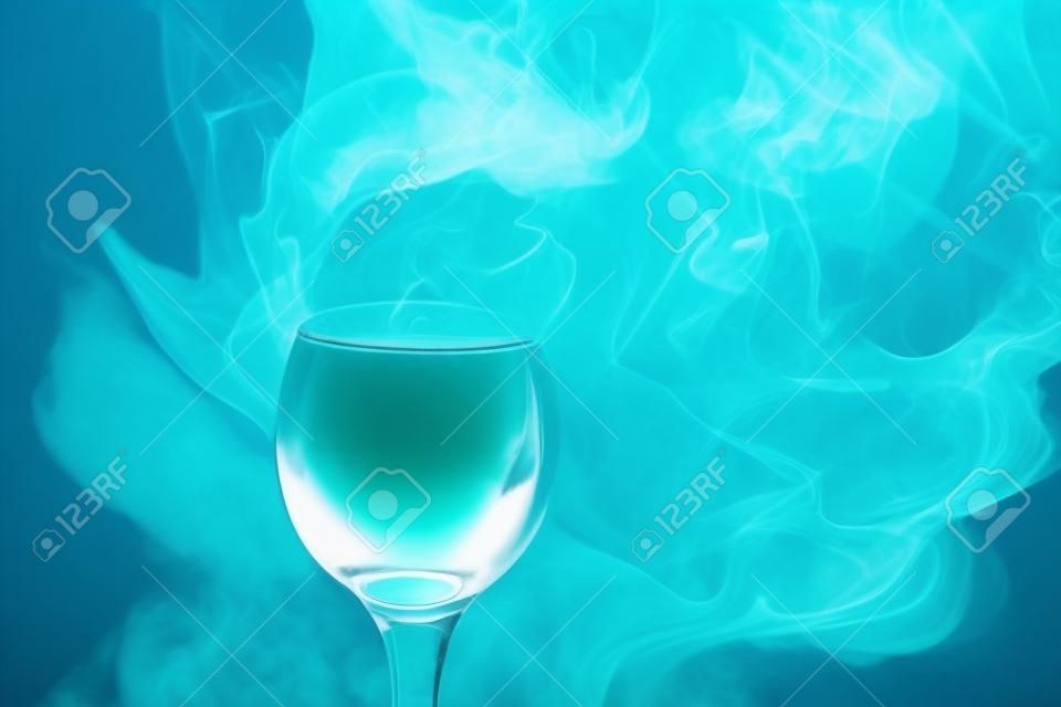 Абстрактное искусство. Кальян синий - зеленый дым в бокал для коктейля на белом фоне. Ведьма зелье фон для Хэллоуина. Необычное дринк-бар. Пить в стекле с эффектом сухого льда.