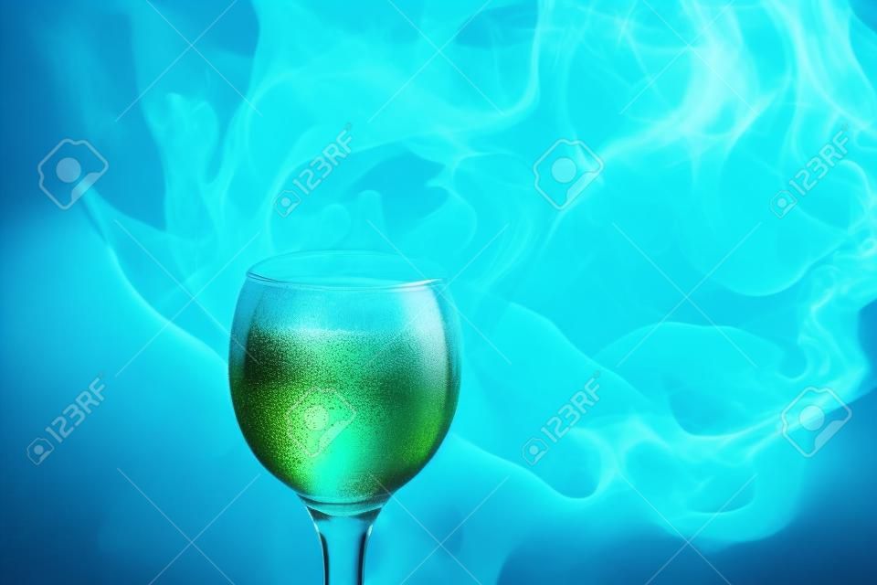 Абстрактное искусство. Кальян синий - зеленый дым в бокал для коктейля на белом фоне. Ведьма зелье фон для Хэллоуина. Необычное дринк-бар. Пить в стекле с эффектом сухого льда.