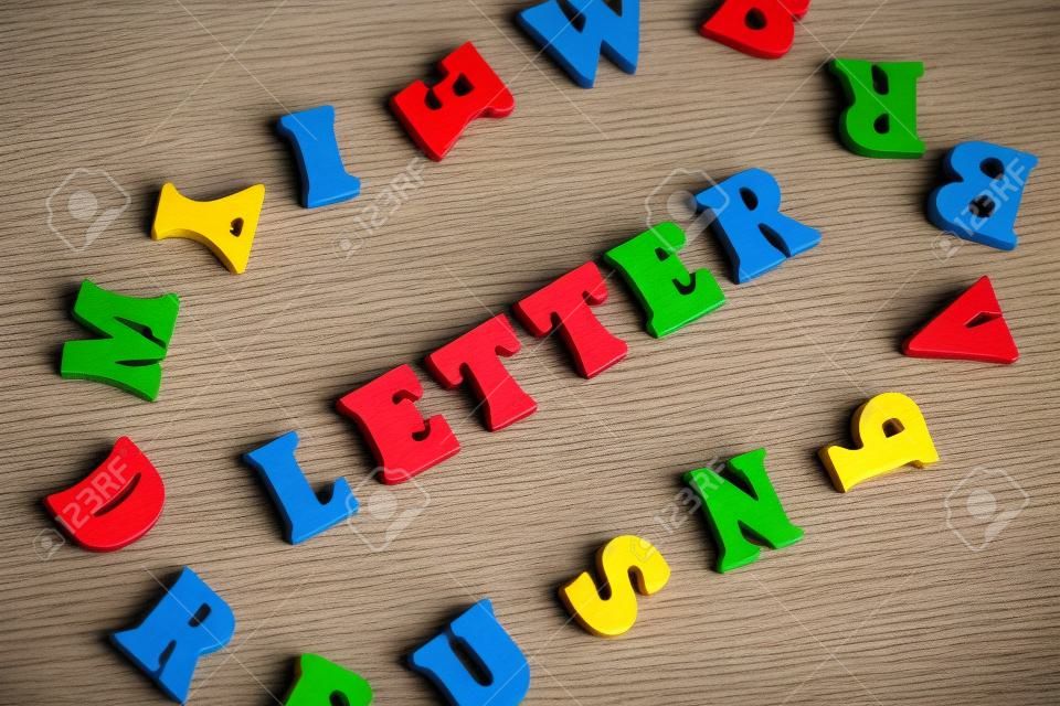 나무 글자로 만든 단어 LETTER. 단어 주위에 여러 가지 빛깔의 글자.