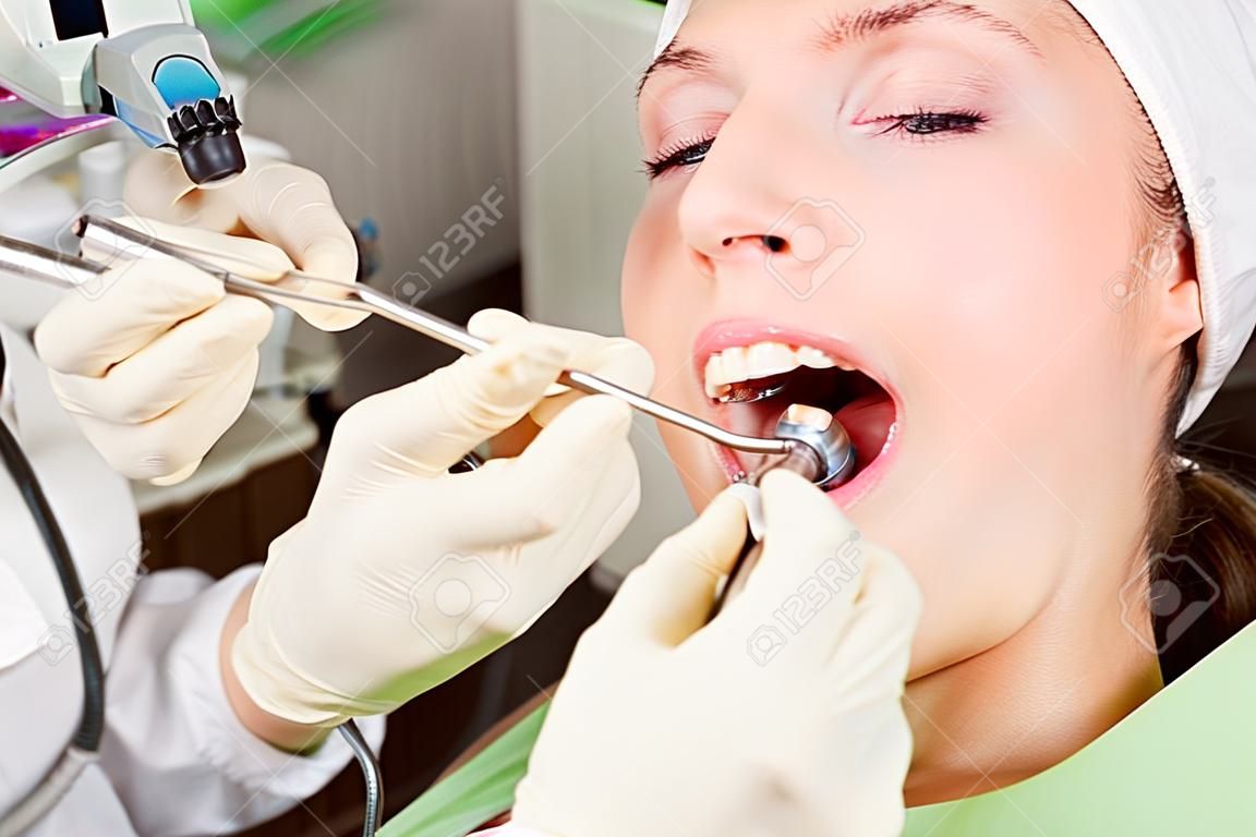 paciente jovem da mulher no dentista com boca aberta durante o procedimento de perfuração, tiro horizontal, close up