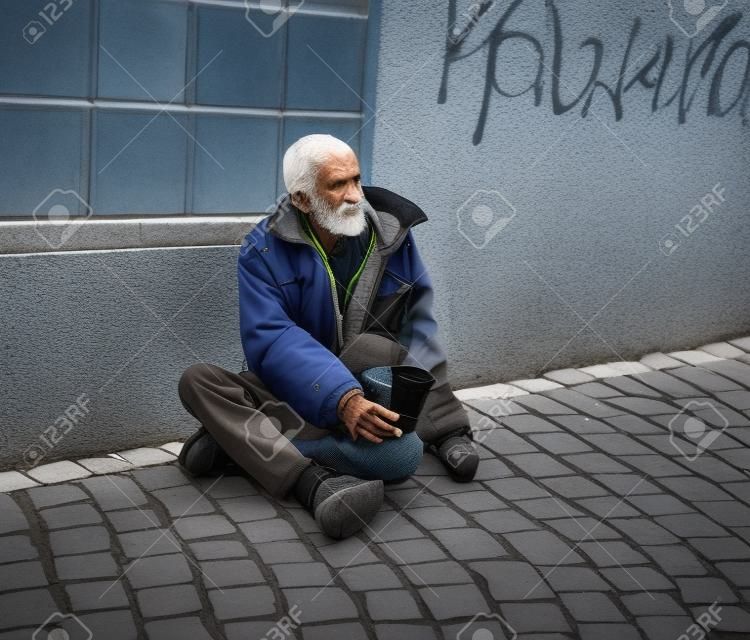 Homeless man on the street of the city. Senior beggar