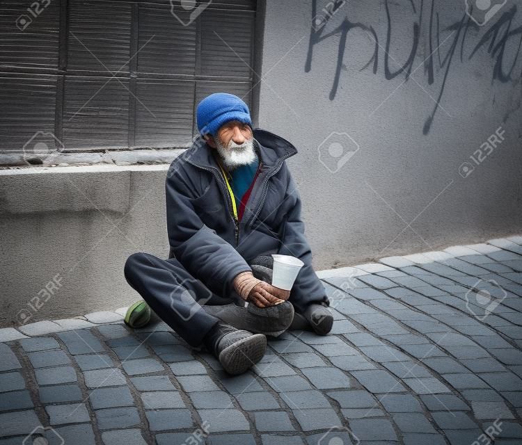 Bezdomny mężczyzna na ulicy miasta. Starszy żebrak