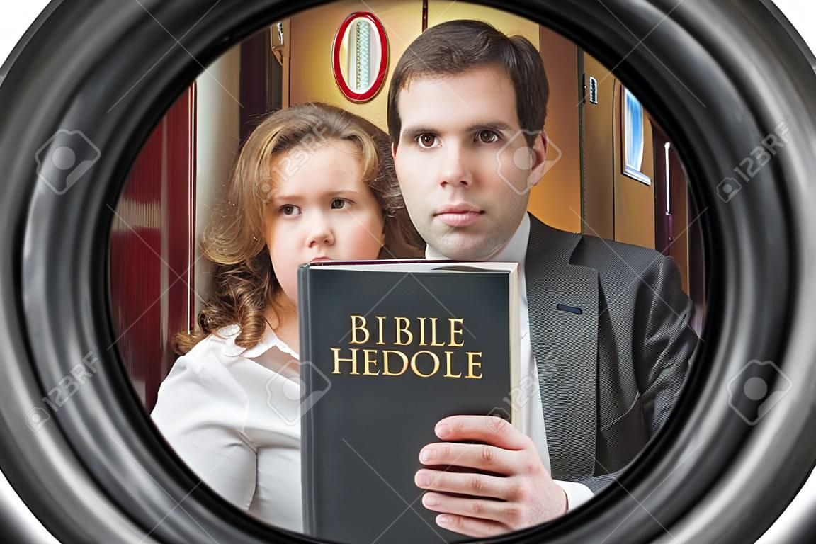 I testimoni di Geova stanno mostrando la Bibbia dietro la porta. Vista dallo spioncino.
