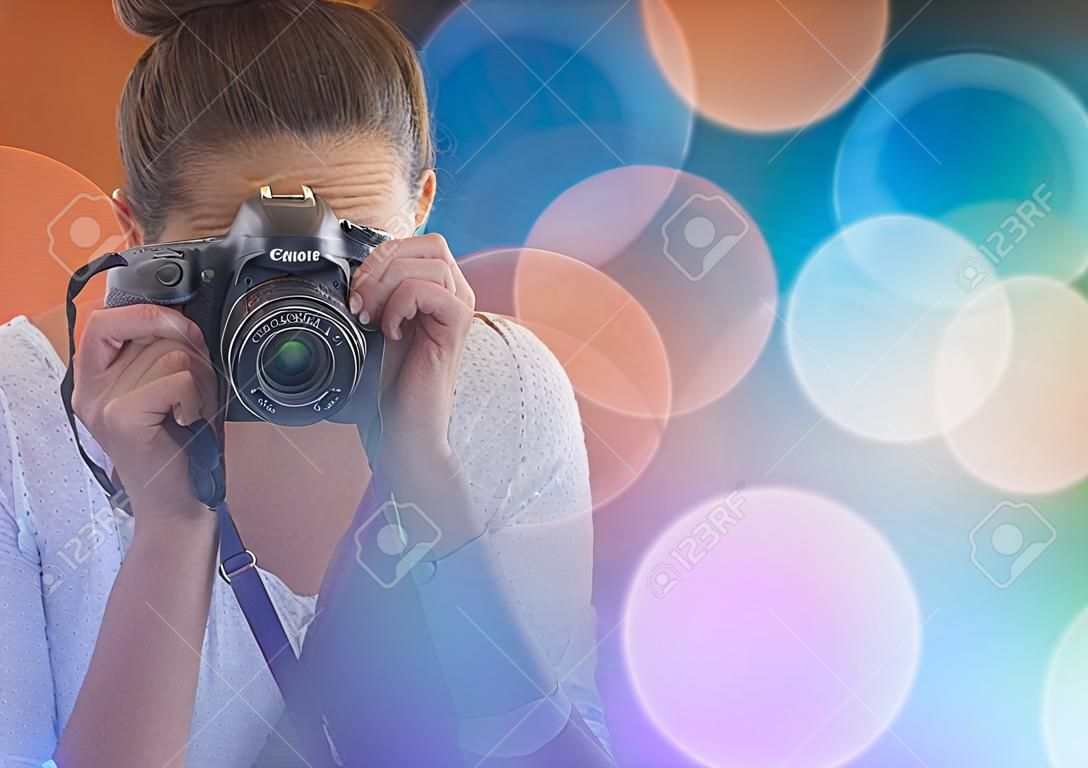 Composto digital do fotógrafo bonito que tira a foto no fundo colorido das luzes