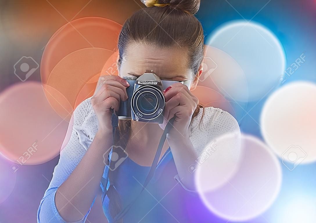 Composite numérique de Jolie photographe prenant la photo dans le fond de lumières colorées