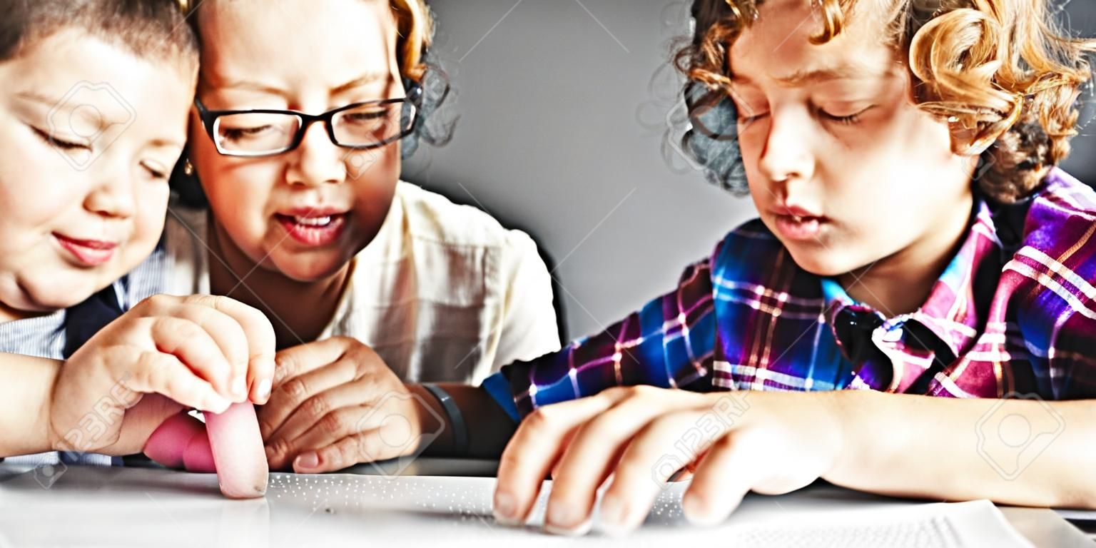 Teacher looking at boy using Braille to read in school