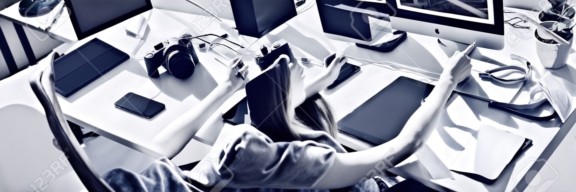 Wysoki kąt widzenia kobiecego grafika używającego tabletu podczas pracy na komputerze w biurze