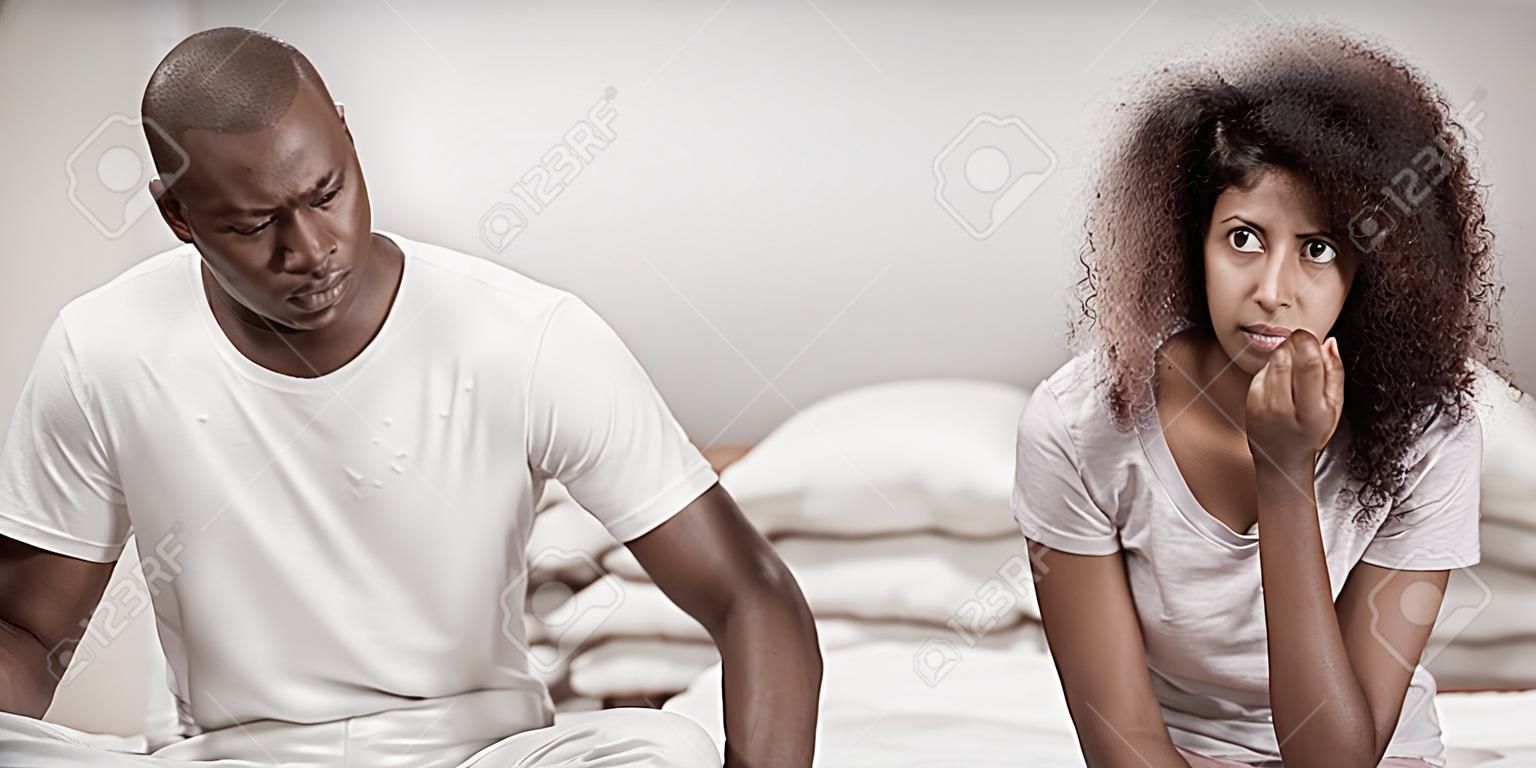 Upset couple ignoring each other after fight on bed in bedroom