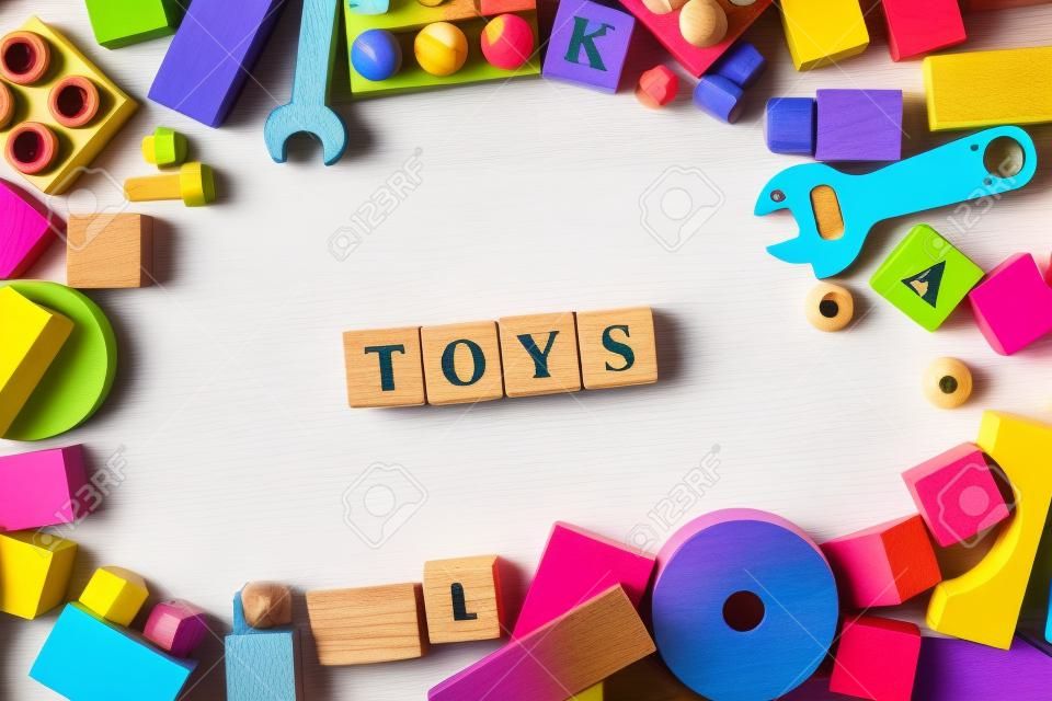 Toys Word Written In Wooden Cubes. Children toys on white background as frame with copy space for text. Top view. Flat lay
