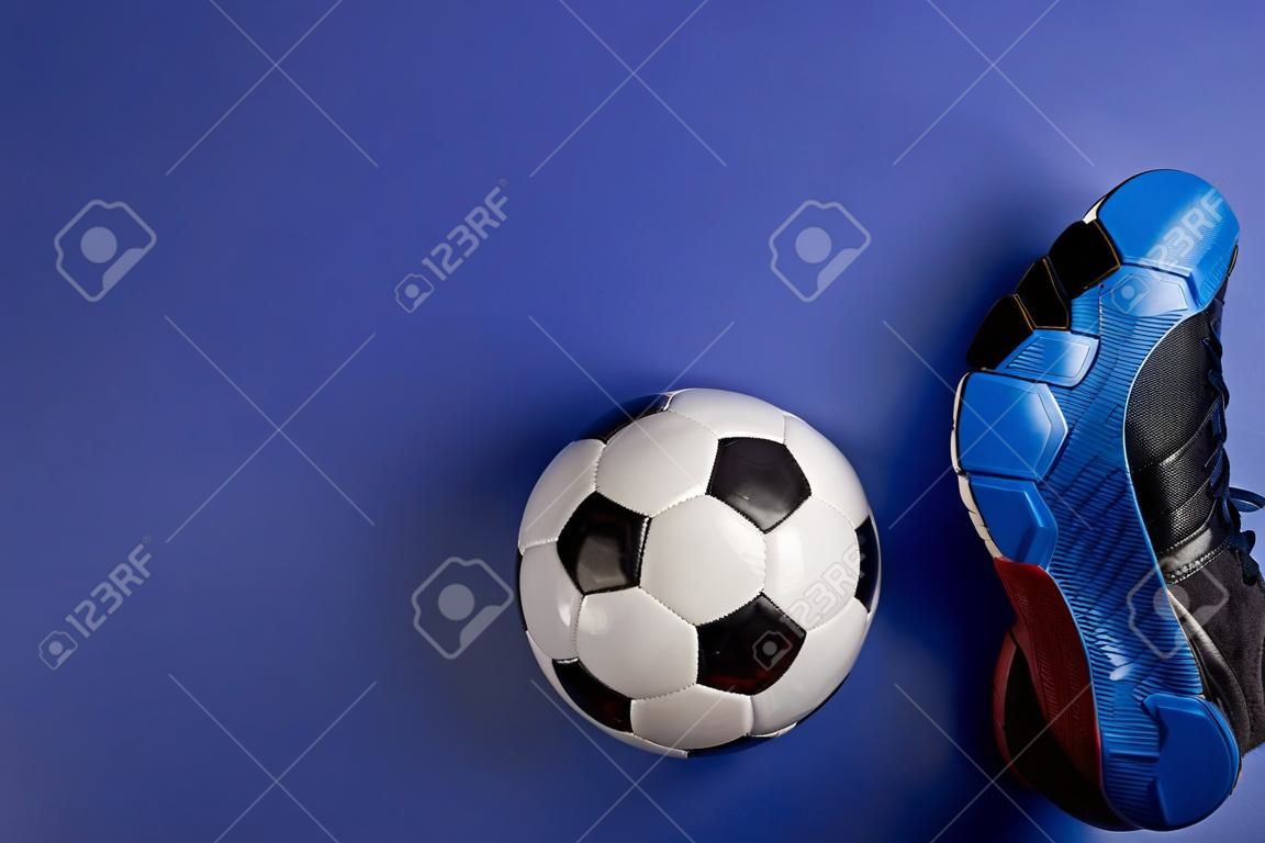 Soccer ball under soccer players feet on blue background