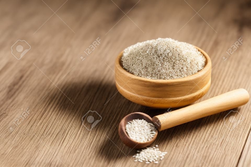 Psyllium Husk seeds, fiber source, in wooden bowl on white wooden background. Closeup with copy space