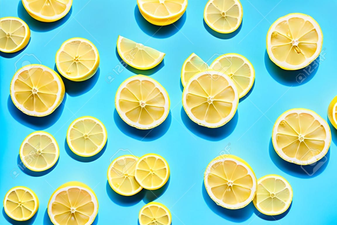 Lemon pattern on bright light blue background. Minimal flat lay food texture. Summer abstract trendy fresh concept.
