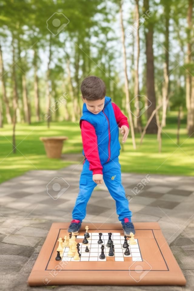 Child playing chess on board game outdoor. Hobby club children playing game chess with figures. Boys characters, childhood of personage, back to school concept.