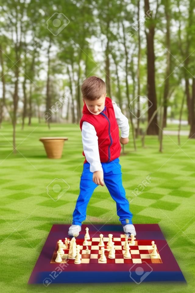 Child playing chess on board game outdoor. Hobby club children playing game chess with figures. Boys characters, childhood of personage, back to school concept.