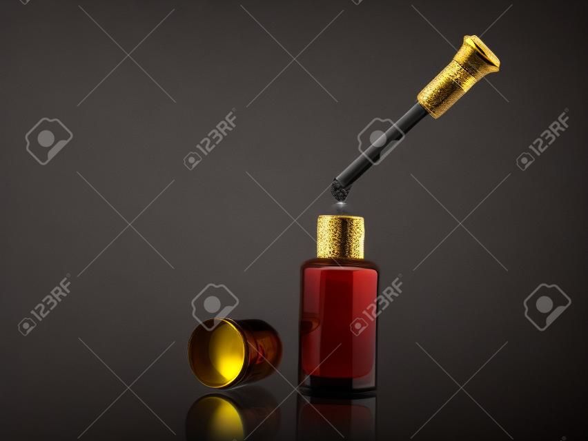 Incenso de óleo de fragrância árabe tradicional em um frasco de vidro e gota de conta-gotas no fundo preto