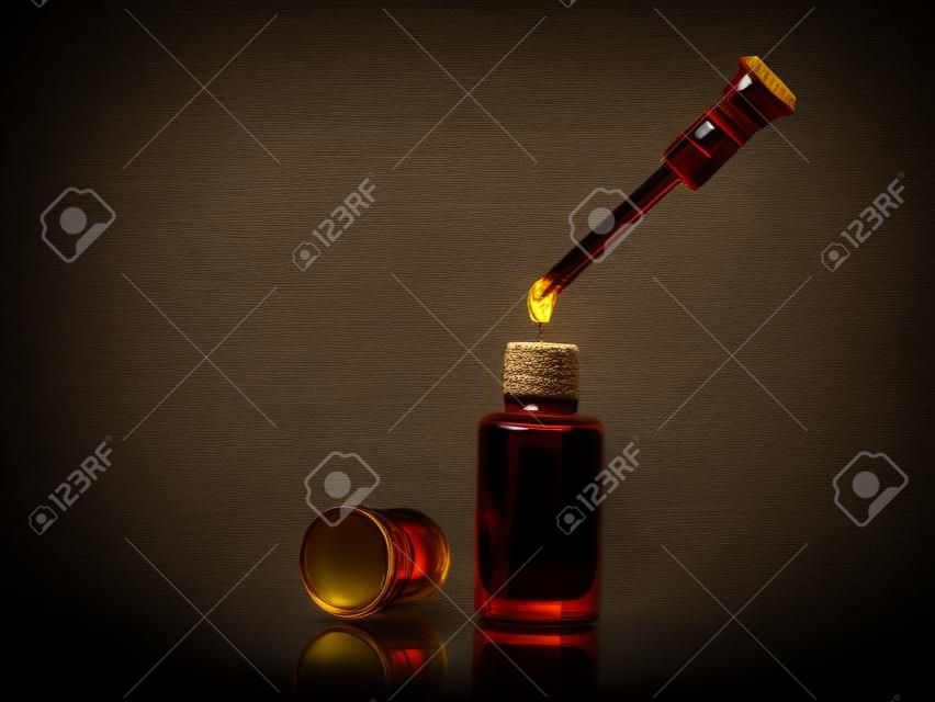 Weihrauch des traditionellen arabischen Duftöls in einem Glasgefäß und Tropfenzähler fallen auf schwarzen Hintergrund