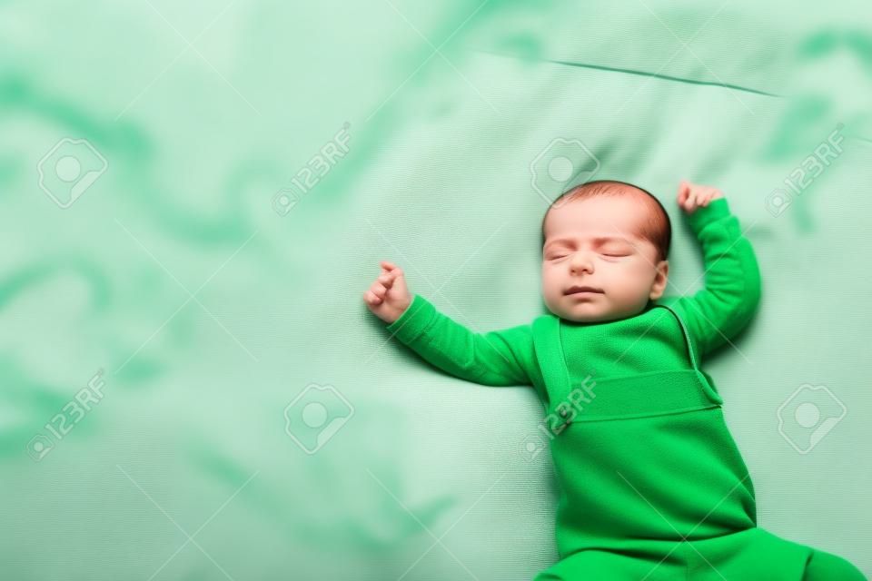 La piccola bambina dorme su un letto con indosso un abito verde, la giostrina le gira addosso.