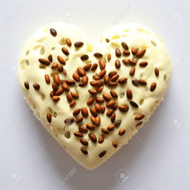 Serce w kształcie drożdżówka z sezame i słonecznika samodzielnie na białym tle