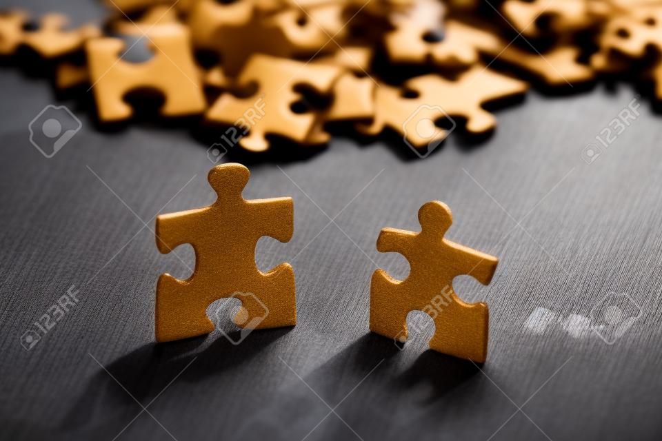 Closeup of two jigsaw puzzle pieces on table. Shallow depth of field