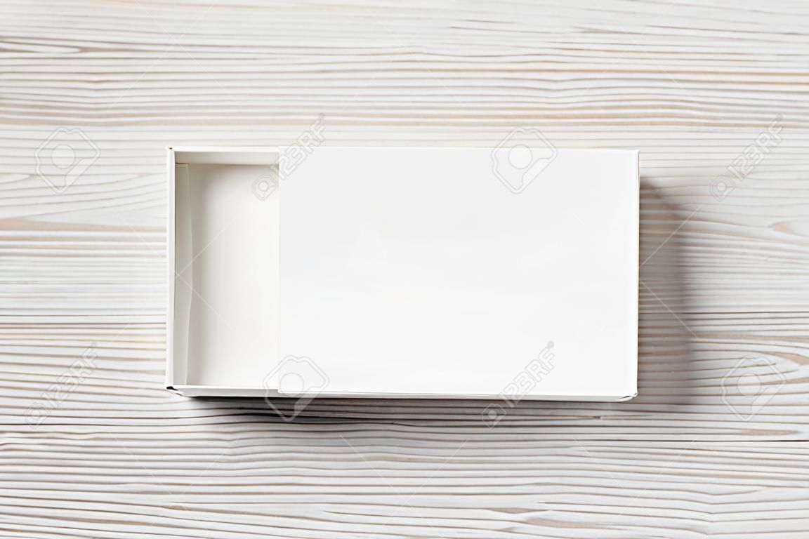 Caja de papel blanco en blanco sobre fondo de mesa de madera clara. Maqueta de paquete. Maqueta de marca. Vista superior. Endecha plana.